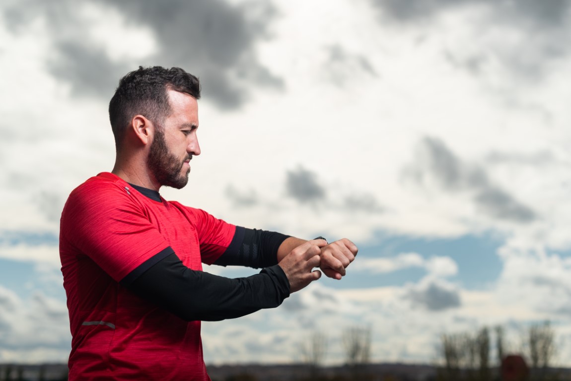Young runner man training and checking stopwatch.